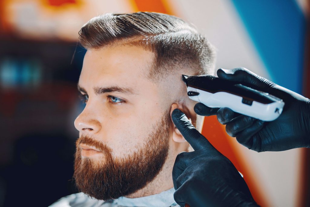 Bărbat stylish așezat într-un barbershop modern, reflectând stilul contemporan.